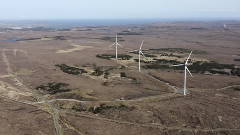 Static-drone-shot-of-a-wind-farm-with-spinning-wind-turbines-generating-green,-sustainable-energy
