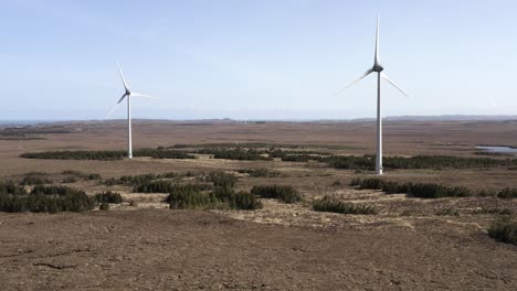 Drone-shot-two-wind-turbines-at-a-wind-farm-generating-green,-sustainable-energy