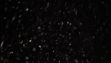 Rain-and-snow-falling-in-the-dark-sky-of-a-winter-night,-sleet-on-black-background