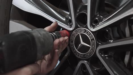 A-mechanic-unscrews-wheel-studs-using-a-screwdriver-from-a-Mercedes