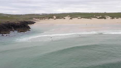 Drone-shot-of-surfers-paddling-at-Eoropie-beach-in-Ness-on-a-sunny,-Summer's-day