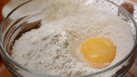 macro-shot-of-a-kitchen-whisk-breaking-a-yellow-egg-in-flour-in-ultra-slow-motion