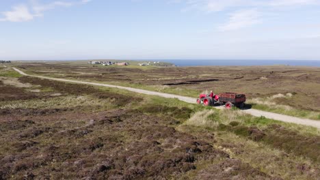 Drone-shot-following-a-tractor-of-a-peat-cutter-driving-peat-harvest-home-from-his-peatland