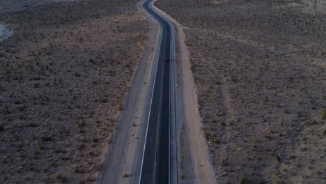 Overhead-shot-revealing-a-car-slowly-driving-towards-Red-Rock-Canyon-at-sunrise