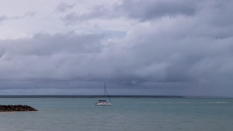 Timelapse-of-storm-clouds-moving-with-anchored-sailing-boat-in-Darwin-Harbour,-Northern-Territory