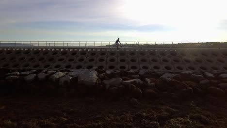 Slow-motion-shot-of-a-man-riding-his-bicycle-by-the-sea