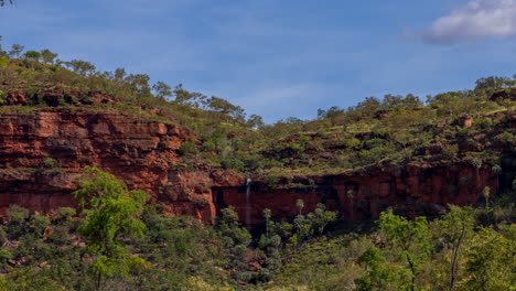 Timelapse-of-a-small-waterfall-as-it-is-flowing-over-a-mountain-face-with-clouds-in-the-Northern-Territory
