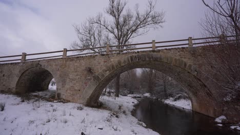 Beautiful-old-bridge-built-by-stone-from-middle-age-on-a-winter-snowy-bacground-in-Albania
