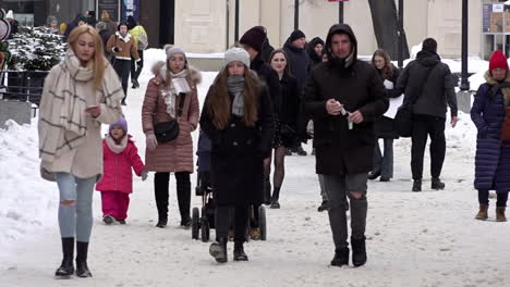 In-slow-motion-men,-women-and-children-walk-along-snow-covered-streets
