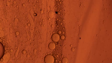 Orangefarbenes-öliges-Gel,-Das-Mit-Ölblasen-über-Eine-Fleckenartige-Oberfläche-Fließt