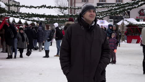 A-man-takes-a-photograph-of-his-family-on-his-smart-phone-as-people-attend-a-Christmas-fair-of-festive-stalls-in-a-snow-covered-town-square