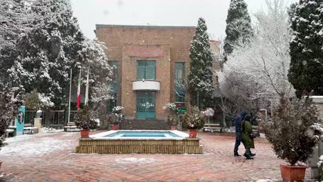 A-lovely-couple-tourist-travel-are-walking-in-a-park-Persian-garden-in-Tehran-in-a-cold-frozen-winter-heavy-snow-shower-snowfall-in-the-city-center-downtown-shopping-in-old-city-in-middle-east-asia