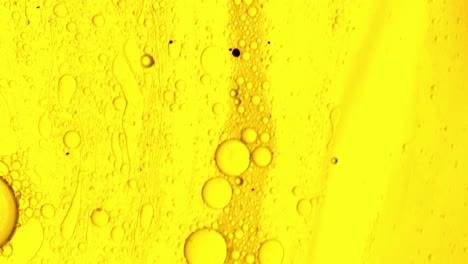 Gelbes-öliges-Gel,-Das-Mit-Ölblasen-über-Eine-Fleckenartige-Oberfläche-Fließt
