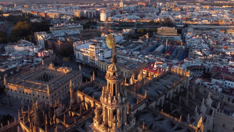 Luftaufnahme-Der-Gotischen-Giralda-Turmstatue-Der-Kathedrale-Von-Sevilla,-Die-Sich-Bei-Sonnenaufgang-über-Der-Skyline-Der-Spanischen-Wahrzeichen-Der-Altstadt-Erhebt