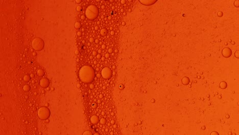 Dirty-orange-oil-flow-with-black-spots-slowly-with-bubbles-and-dust-on-surface