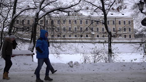 In-slow-motion-men-an-women-in-winter-clothing-walk-along-a-snow-covered-path-and-pass-by-Rzeszow-castle