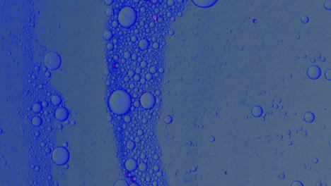 Dirty-blue-oil-flow-with-black-spots-slowly-with-bubbles-and-dust-on-surface