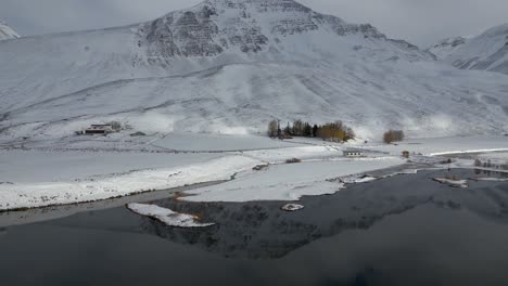 Beautiful-Snowy-Mountain-Reflection-in-Lake-in-Breathtaking-Iceland-Landscape,-Aerial-Establishing-Tilt-up