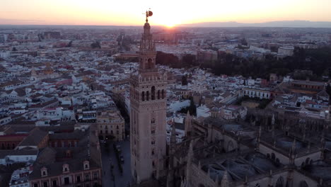Aerial-orbiting-view-around-Giralda-tower-gothic-Seville-cathedral-old-town-Spanish-landmark-skyline-during-sunrise