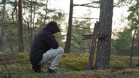 Man-kneeling-and-crying-in-front-of-a-wooden-cross