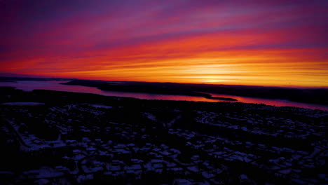 Aerial-view-of-a-vibrant,-colorful-sky-as-dusk-falls-over-the-winter-landscape