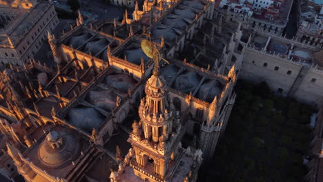 Aerial-rotation-around-the-top-Giralda-tower-of-the-largest-gothic-cathedral-in-the-world-in-Seville,-Spain