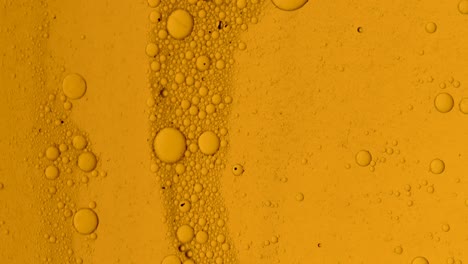 Dirty-golden-oil-flow-with-black-spots-slowly-with-bubbles-and-dust-on-surface