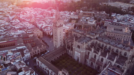 Seville-cathedral-gothic-Giralda-tower-statue-aerial-view-descending-to-old-town-Spanish-landmark-skyline-at-sunrise