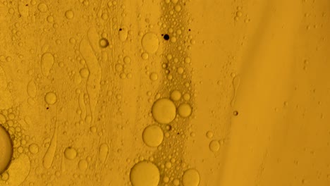 Goldenes,-öliges-Gel,-Das-Mit-Ölblasen-über-Eine-Fleckenartige-Oberfläche-Fließt