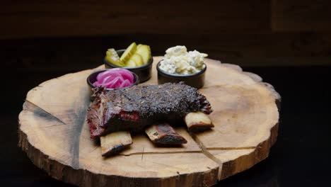 Barbecue-ribs-from-a-smoker-on-the-wooden-plate-with-side-pickles-trucking-shot