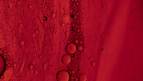 Rotes-öliges-Gel,-Das-Mit-Ölblasen-über-Eine-Fleckenartige-Oberfläche-Fließt