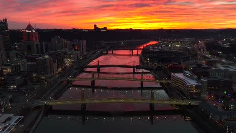 Aerial-backwards-reveal-of-beautiful-sunset-over-Allegheny-River-in-Pittsburgh,-PA