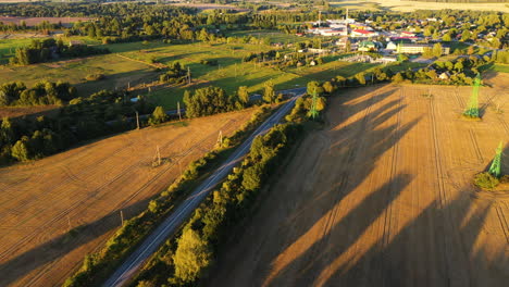 Roads-leading-to-small-countryside-town-in-sunny-evening,-aerial-drone-view