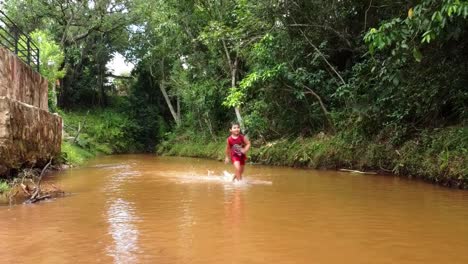 hispanic-boy-running-down-the-river-stream-in-Paraguay