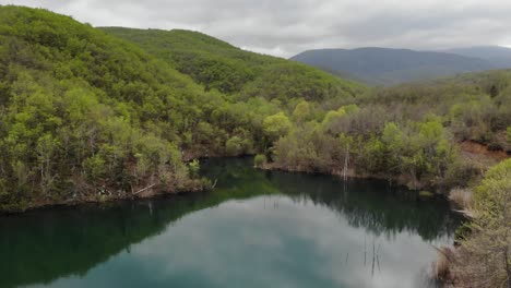 Video-De-Drones-Vuelo-Bajo-Sobre-El-Lago-En-El-Bosque-De-Montaña-Nublado-Soleado