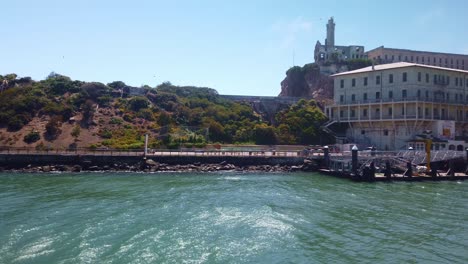Gimbal-Nahaufnahme-Des-Landungsdocks-Und-Des-Willkommenszentrums-Auf-Der-Insel-Alcatraz-Von-Einem-Fahrenden-Boot-In-Der-Bucht-Von-San-Francisco-Aus