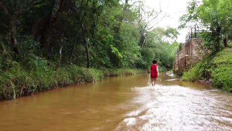 Young-boy-running-down-the-river-in-Paraguay,-South-America