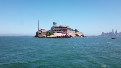 Gimbal-Bewegungsaufnahme,-Die-Sich-Mit-Einem-Boot-Der-Rückseite-Der-Insel-Alcatraz-Nähert,-Wobei-Im-Hintergrund-Die-Bay-Bridge-Und-San-Francisco-Zu-Sehen-Sind