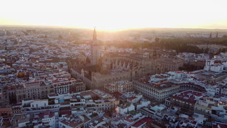 Epic-aerial-view-of-the-Cathedral-of-Seville,-largest-gothic-cathedral-in-the-world-at-sunset-time
