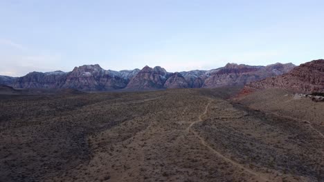 Aerial-shot-of-the-distant-Red-Rock-Canyon-and-the-desert-landscape-at-sunrise