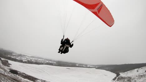 Drone-closely-following-paraglider-during-landing-and-snowfall