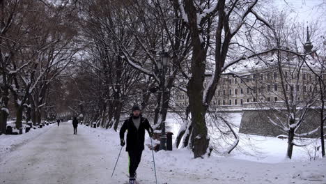 Ein-Mann-Benutzt-Skier-Und-Stöcke,-Um-Einen-Schneebedeckten-Weg-Vor-Dem-Schloss-Rzeszów-Entlangzufahren