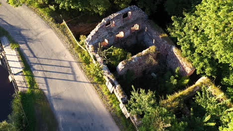 Abandoned-overgrown-water-mill-ruins-in-aerial-view-next-to-road