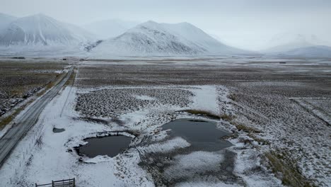 Paisaje-De-Islandia-Con-Un-Camino-Que-Conduce-A-Montañas-Nevadas,-Antena