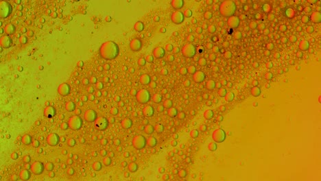 Eine-Grün-orangefarbene,-Fettige-Flüssigkeit-Fließt-über-Eine-Oberfläche-Mit-Blasen-Und-Schmutz