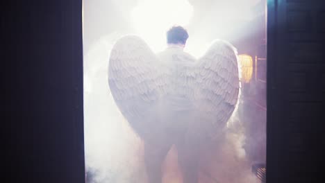 Cinematic-rising-shot-of-a-man-wearing-angel-wings-rising-through-the-smoke-cloud