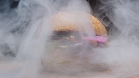 Pulled-pork-sandwich-in-a-butter-bun-with-pickles-and-bbq-sauce-covered-with-a-thick-cloud-of-smoke---close-up