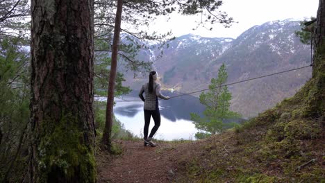 Woman-stops-at-scenic-viewpoint-overlooking-Norwegian-fjord-while-hiking