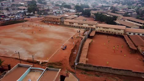 Aerial-view-approaching-people-playing-street-football-in-the-city-of-Yaounde,-Cameroon