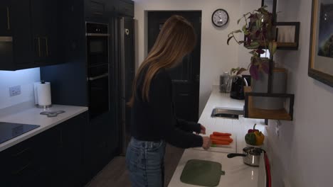 Wide-shot-of-a-female-model-prepping-food,-cutting-carrots-then-putting-in-pan-and-walking-off-in-a-modern-kitchen